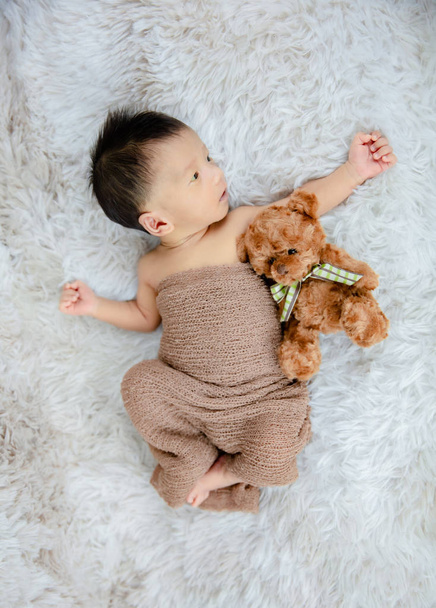 Küçük bebek uzanmış oyuncak ayıya sarılıyor. - Fotoğraf, Görsel