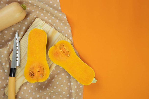 Cut of butternut squash on tablecloth with orange background - 写真・画像