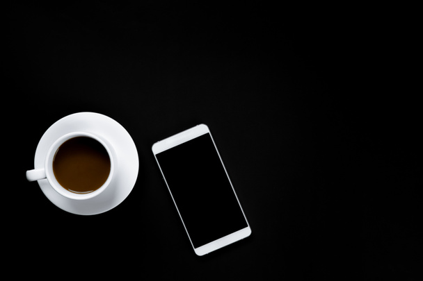 Smartphone und Tasse Kaffee auf schwarzem Hintergrund  - Foto, Bild