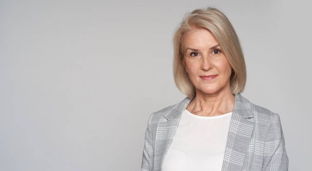 Senior blonde woman is smiling isolated on grey - Fotó, kép