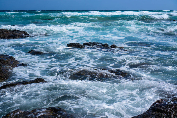 Hullámok sziklás strandon nappal - Fotó, kép