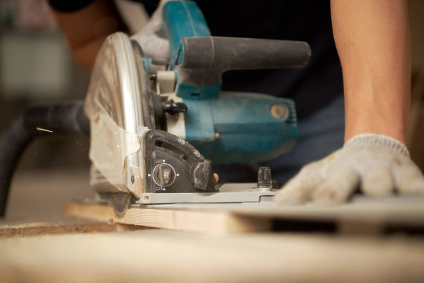 Hands of carpenter man sawing wooden boards with jigsaw - 写真・画像
