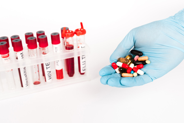 vista recortada de científico en guantes de látex sosteniendo pastillas cerca de tubos de ensayo con letras aisladas en blanco
  - Foto, imagen