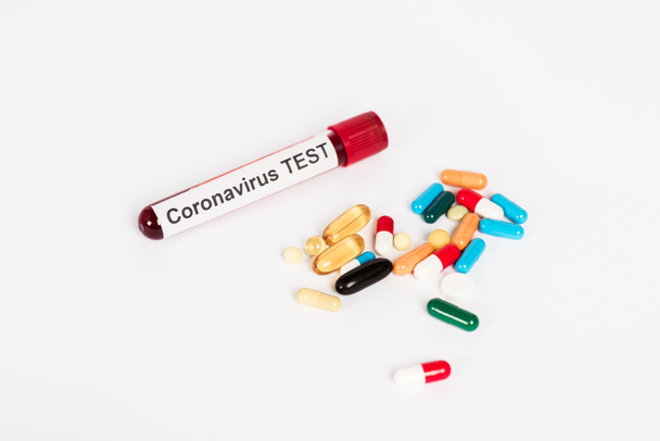 píldoras de colores cerca de la muestra con letras de prueba coronavirus aislados en blanco
  - Foto, Imagen