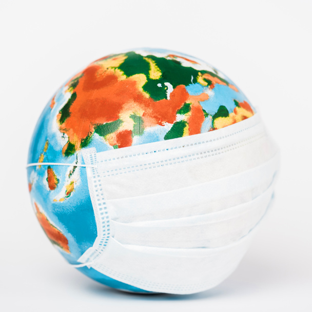 close up of globe in medical mask on white  - Foto, afbeelding