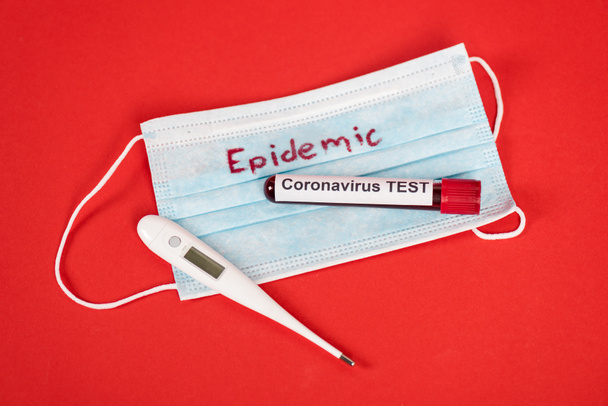 top view of sample with coronavirus test near protective medical mask with epidemic lettering and digital thermometer on red  - Photo, Image