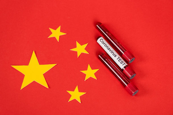 κορυφαία άποψη των δειγμάτων με γράμματα δοκιμής coronavirus κοντά στην κόκκινη κινεζική σημαία  - Φωτογραφία, εικόνα