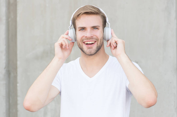 Wireless Earpiece. Handsome guy wear headphones grey background. Man listen modern music. Modern technology. Hobby leisure. Foldable Stereo Headphones. Noise Reduction. Modern and contemporary music - Fotó, kép