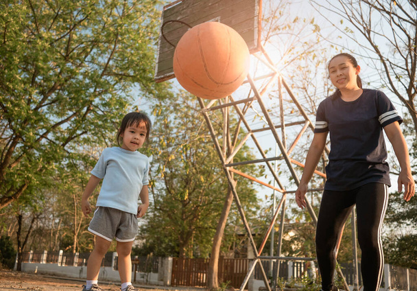 lindo poco asiático niño jugando baloncesto con su madre en pl
 - Foto, imagen