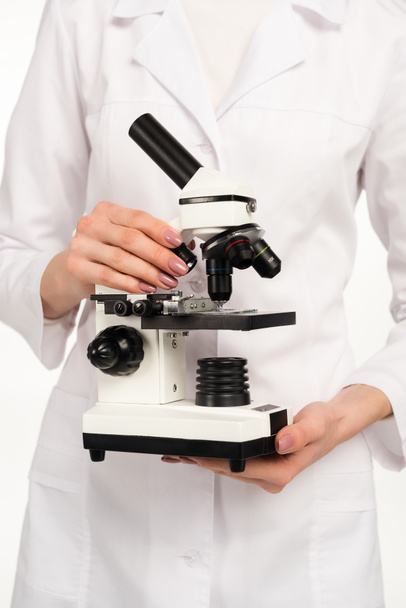 przycięty widok naukowca trzymającego mikroskop wyizolowany na białym  - Zdjęcie, obraz