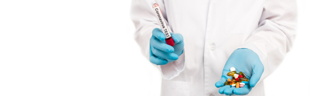 ホワイトに隔離されたコロナウイルス検査のレタリングと錠剤でサンプルを保持する科学者のパノラマ写真  - 写真・画像