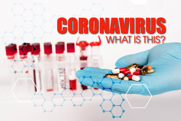 καλλιεργημένη άποψη του επιστήμονα στο γάντι λατέξ κρατώντας χάπια κοντά σε δοκιμαστικούς σωλήνες και coronavirus τι είναι αυτό το γράψιμο στο λευκό  - Φωτογραφία, εικόνα