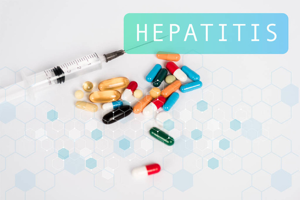 värikäs pillereitä lähellä ruiskua ja hepatiitti kirjoitus valkoinen
  - Valokuva, kuva