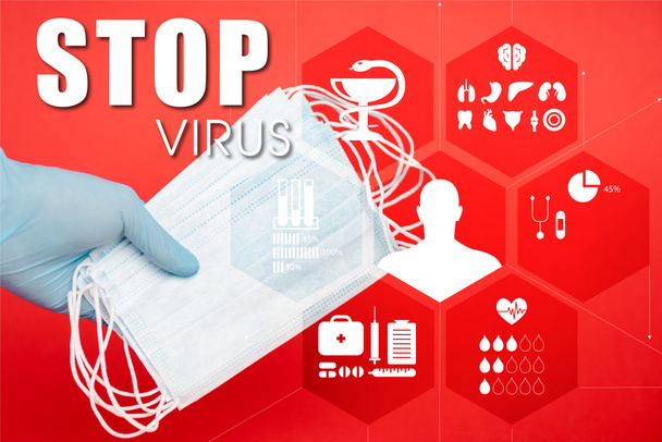 cropped view of scientist holding medical masks near stop virus lettering on red  - Foto, Bild