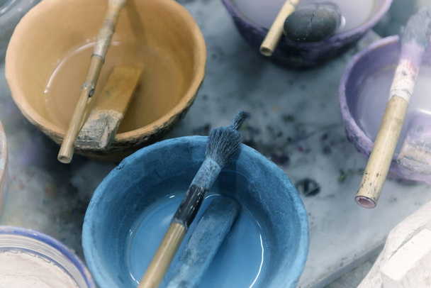 Paint in bowls with simple brushes in an artist studio.  - Photo, Image