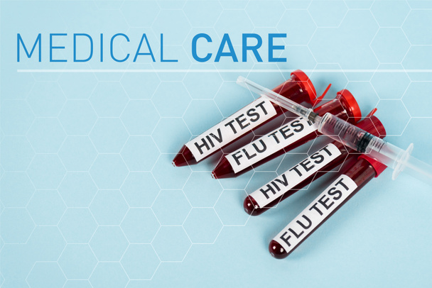 top view of syringe on samples with hiv test and flu test near medical care lettering on blue  - Foto, Imagem