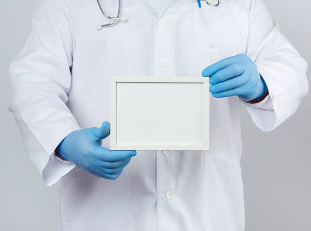 médico masculino con un abrigo médico blanco y guantes de látex azul sostiene
  - Foto, imagen