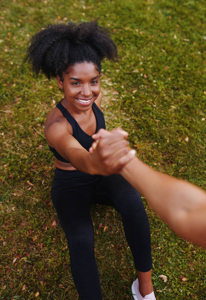 An above view of smiling african american sporty young woman getting help from her friends while doing workouts in park - Foto, Bild