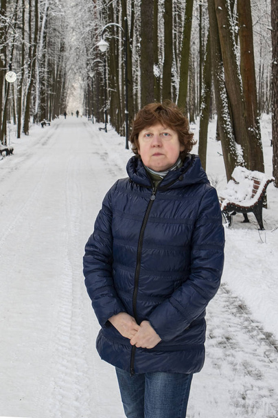 El invierno. Una dama con una chaqueta deportiva azul está de pie en un callejón en un bosque nevado
 - Foto, imagen