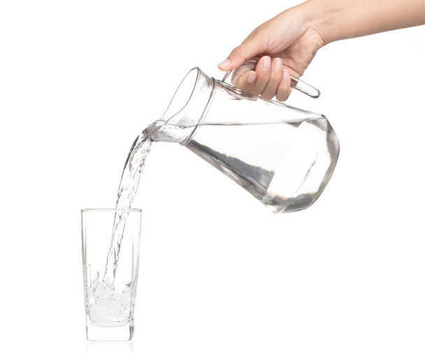Hand pouring water from glass jug to glass isolated on a white b - Valokuva, kuva