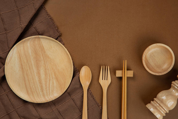 Set de utensilios de cocina con mantel marrón sobre fondo marrón
 - Foto, Imagen