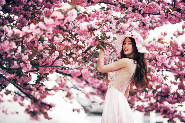 girl stands on a background of a blossoming tree in spring - Foto, Bild