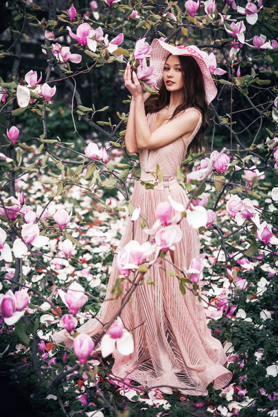 a full-length girl holding a magnolia tree in spring - Foto, immagini