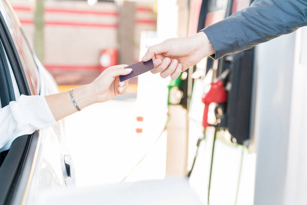 Mão cortada do cliente que faz o pagamento através do cartão de crédito no posto de gasolina
 - Foto, Imagem