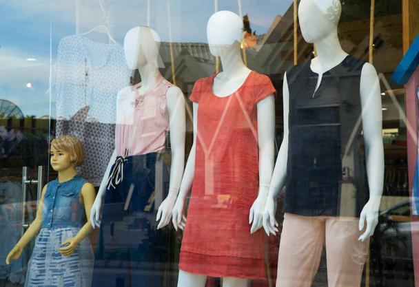 Manekiny reklamują letnie ubrania za szkłem. - Zdjęcie, obraz