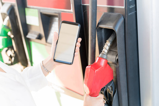 Imagem cortada da mulher fazendo o pagamento através do smartphone no posto de gasolina self-service
 - Foto, Imagem