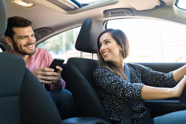 Sorridente conducente femminile sicuro di parlare con il cliente maschile in taxi
 - Foto, immagini