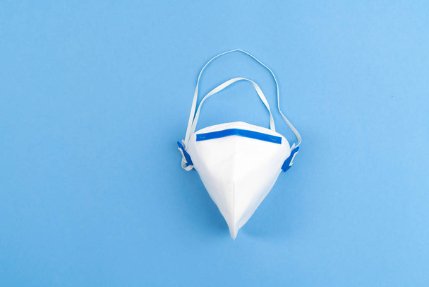 Белая медицинская маска на синем фоне. Нехватка воздушной маски во время эпидемии. Вирус Короны, профилактика ковида-19. Никто
 - Фото, изображение