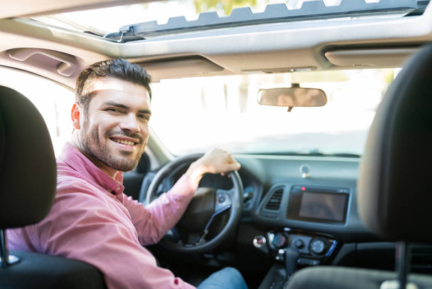 Confiante hispânico médio adulto homem sorrindo enquanto dirige carro novo
 - Foto, Imagem