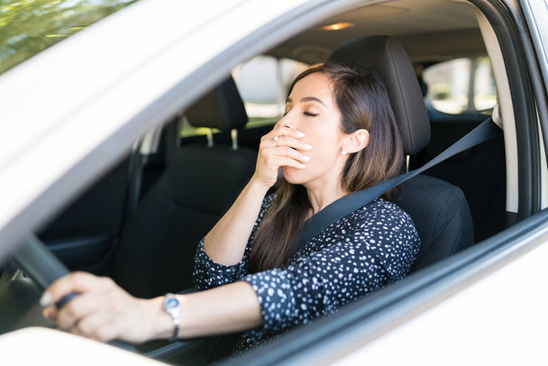 交通中に車で待っている間にあくびをする退屈女性 - 写真・画像