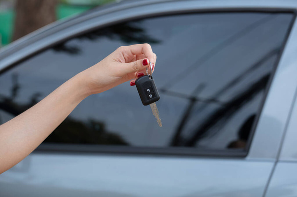 Hand holding car keys with car on background - Foto, afbeelding