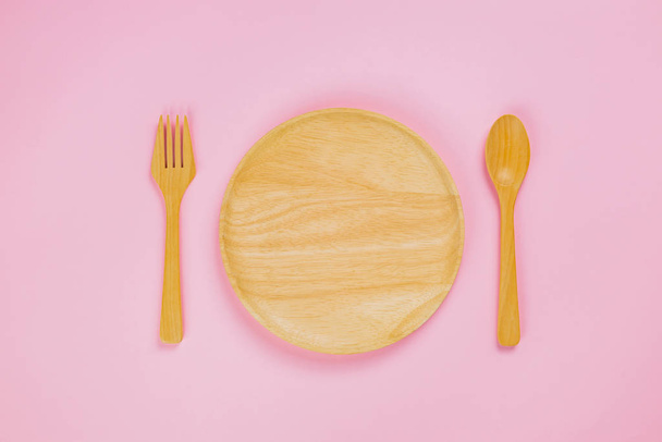 Sluiten Up van houten schotel lepel en vork op roze achtergrond - Foto, afbeelding