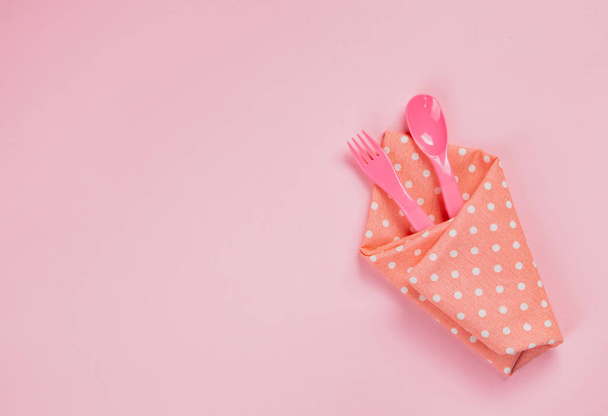 Cucchiaio di plastica, forchetta e tovagliolo di stoffa rosa a pois sul retro rosa
 - Foto, immagini