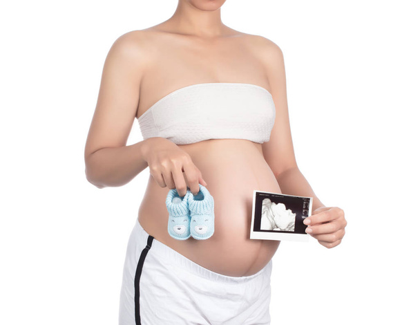 Mulher grávida mão segurando bebê botas de crochê e foto de ultr
 - Foto, Imagem