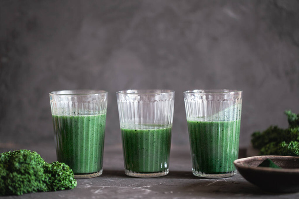 A healthy vegan drink green kale smoothie with spirulina for detox on dark background - Fotó, kép