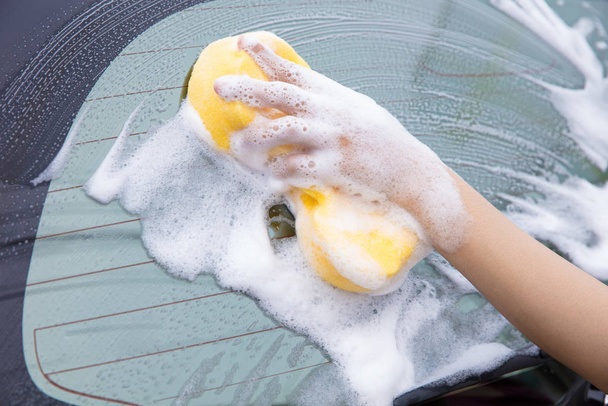 очистка лобового стекла автомобиля с желтой пены губки
. - Фото, изображение