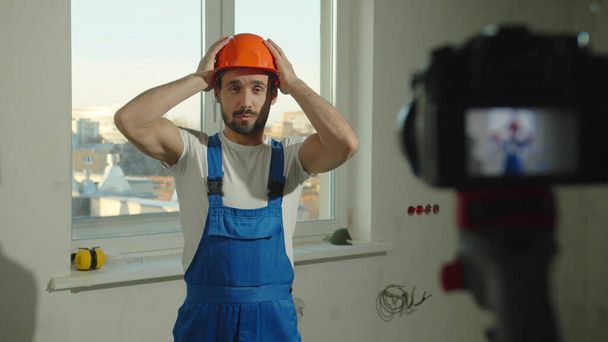 Zeitlupe, Bauarbeiter setzt Helm auf und spricht vor Kamera - Foto, Bild