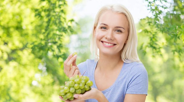 happy woman eating grapes - Foto, afbeelding