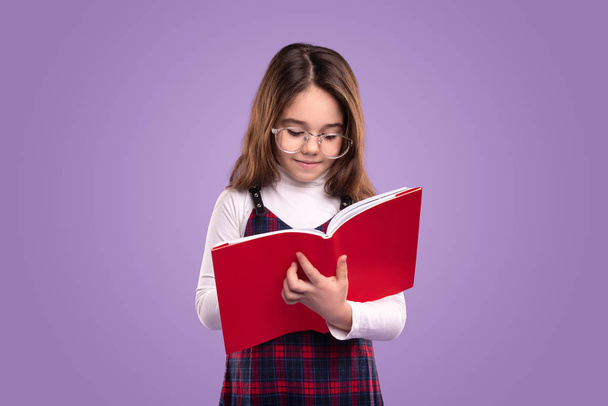Clever little schoolgirl reading book - Valokuva, kuva