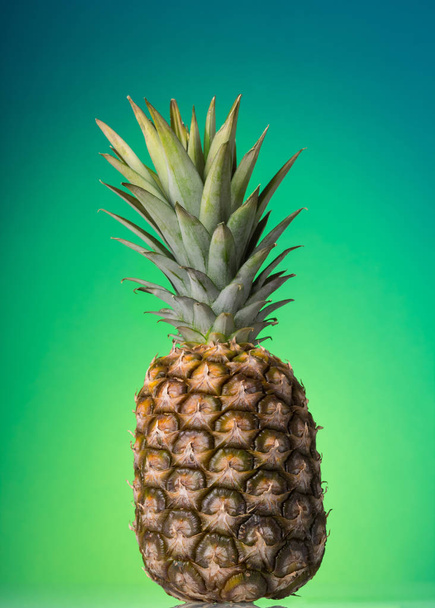 Large ripe pineapple with stalk, on green - Φωτογραφία, εικόνα