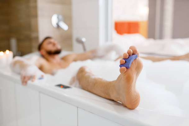Uomo sdraiato in bagno con schiuma al mattino. Persona maschile rilassarsi in bagno, pelle e trattamenti per il corpo procedure
 - Foto, immagini