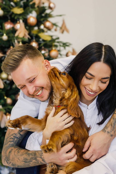 young beautiful couple in white clothes having fun with a small dog in their apartment - Foto, Imagen