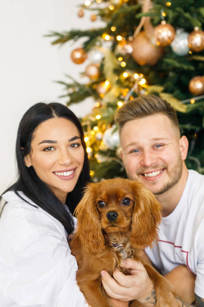 young beautiful couple in white clothes having fun with a small dog in their apartment - Foto, Imagen