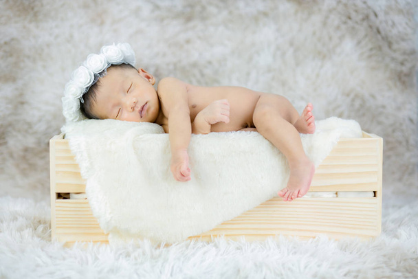 Un bebé recién nacido durmiendo en una caja de madera . - Foto, Imagen