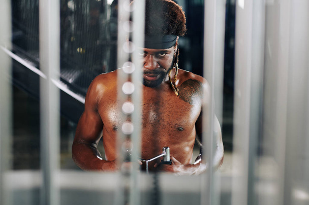 Poziome ujęcie skoncentrowanego Afroamerykanina robiącego ćwiczenia wzmacniające patrząc w kamerę - Zdjęcie, obraz
