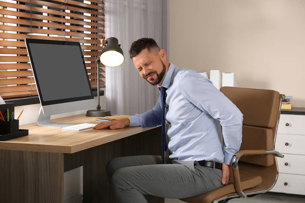 Man suffering from hemorrhoid at workplace in office - Fotó, kép